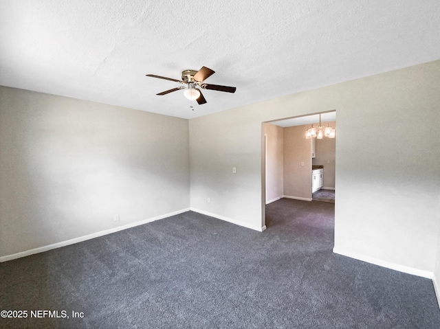 spare room with ceiling fan with notable chandelier, baseboards, dark carpet, and a textured ceiling