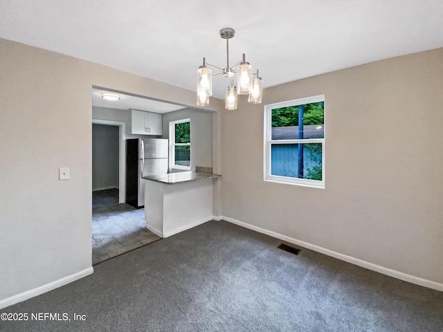 unfurnished room featuring dark colored carpet, visible vents, baseboards, and an inviting chandelier