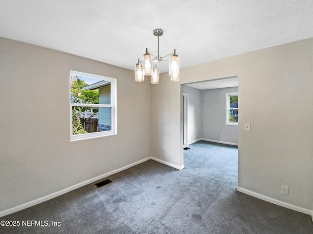 empty room with visible vents, plenty of natural light, baseboards, and dark colored carpet