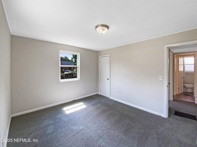 unfurnished room featuring baseboards and dark colored carpet