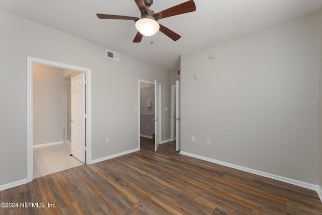 unfurnished bedroom featuring ceiling fan, a closet, a walk in closet, and wood-type flooring