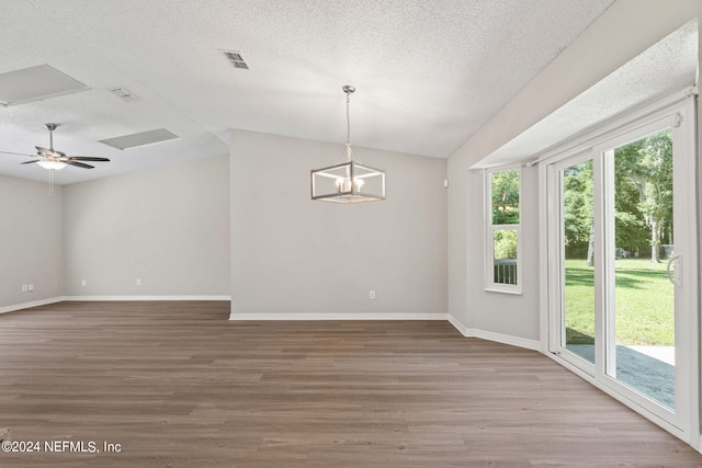 empty room featuring a textured ceiling, ceiling fan with notable chandelier, wood-type flooring, and lofted ceiling