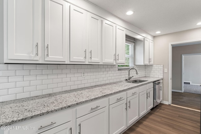 kitchen with light stone countertops, dishwasher, sink, dark hardwood / wood-style floors, and white cabinets