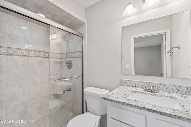 bathroom featuring vanity, a shower with shower door, and toilet