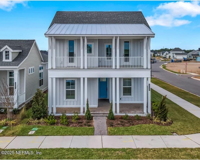 view of front facade with board and batten siding, metal roof, a porch, and a balcony