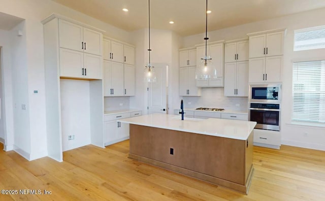 kitchen featuring light countertops, appliances with stainless steel finishes, backsplash, and white cabinetry