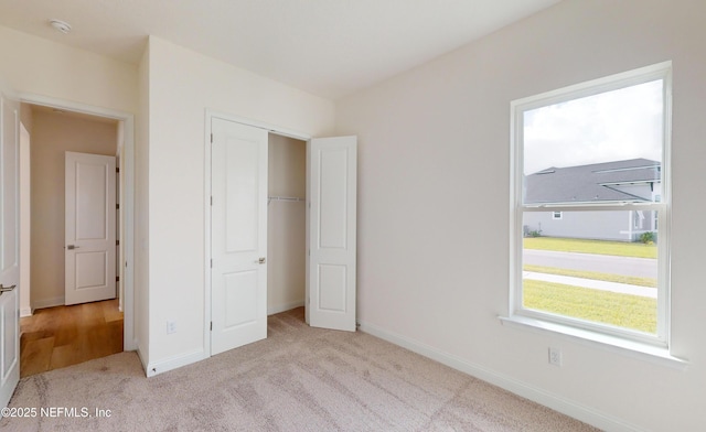 unfurnished bedroom featuring light colored carpet and a closet