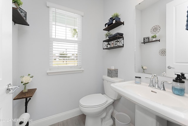 bathroom with toilet, a sink, baseboards, and wood finished floors