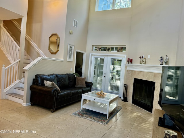 tiled living room featuring a fireplace, a high ceiling, and french doors