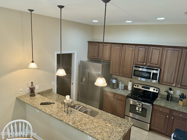 kitchen with light stone counters, kitchen peninsula, hanging light fixtures, and appliances with stainless steel finishes