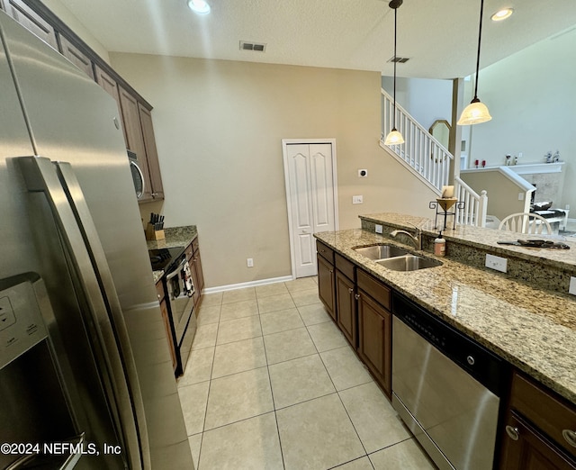 kitchen featuring light stone countertops, sink, hanging light fixtures, light tile patterned floors, and appliances with stainless steel finishes