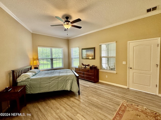 bedroom with ceiling fan, crown molding, light hardwood / wood-style floors, and a textured ceiling