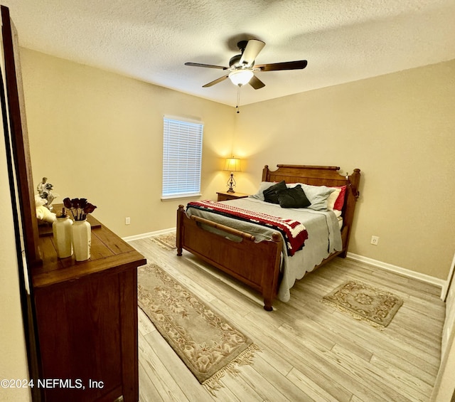 bedroom with ceiling fan, light wood-type flooring, and a textured ceiling