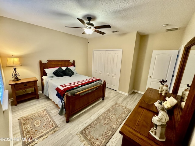 bedroom featuring ceiling fan, a closet, a textured ceiling, and light hardwood / wood-style flooring