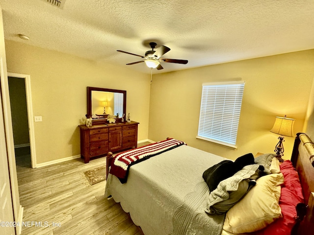 bedroom with a textured ceiling, light wood-type flooring, and ceiling fan