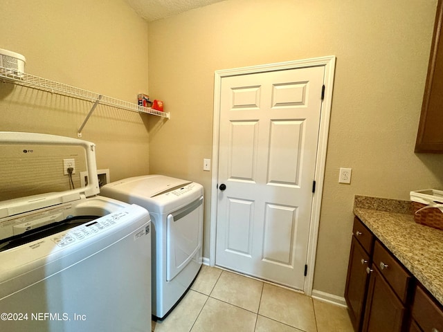 clothes washing area with cabinets, light tile patterned flooring, washing machine and dryer, and a textured ceiling