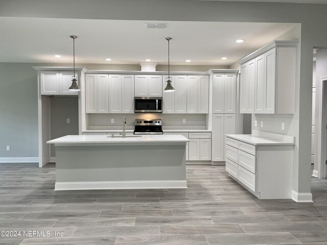 kitchen featuring appliances with stainless steel finishes, sink, white cabinets, and pendant lighting