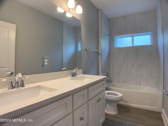 full bathroom with tiled shower / bath combo, double sink, toilet, and vanity with extensive cabinet space