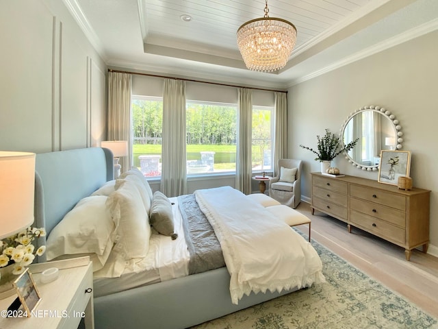 bedroom featuring a raised ceiling, light wood-type flooring, an inviting chandelier, and crown molding