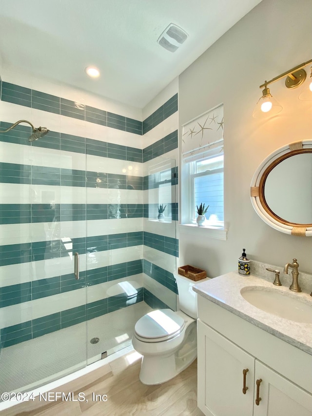 bathroom with tile patterned floors, vanity, a shower with shower door, and toilet