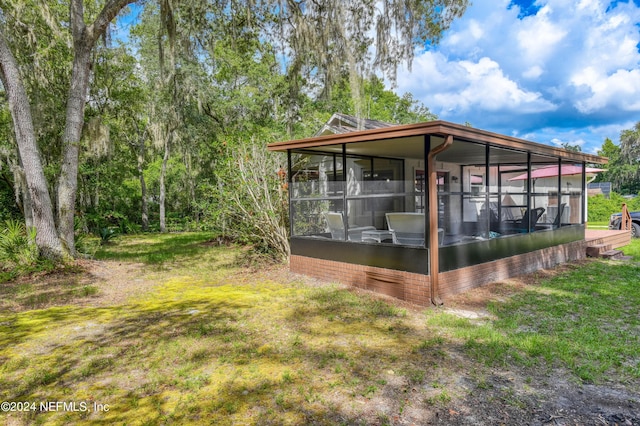 view of side of property featuring a lawn and a sunroom