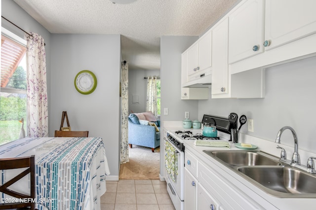 kitchen featuring white cabinets, white gas range oven, a healthy amount of sunlight, and sink