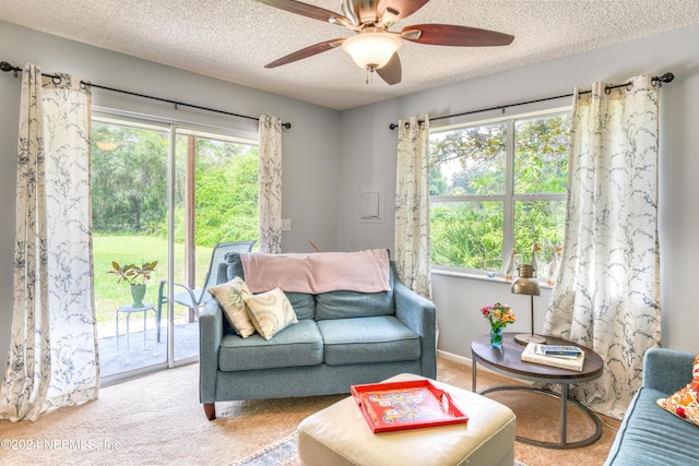 living room with light carpet, ceiling fan, and a textured ceiling