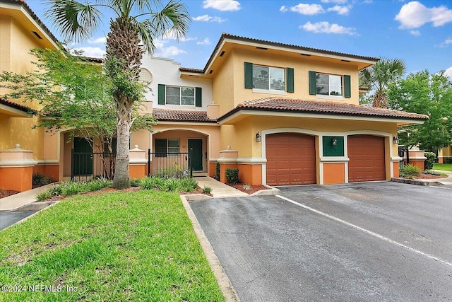 mediterranean / spanish-style house with a garage and a front lawn