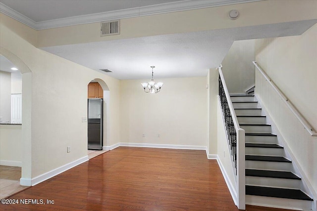 interior space with an inviting chandelier, wood-type flooring, and ornamental molding