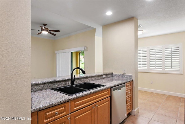 kitchen with sink, light tile patterned floors, crown molding, dark stone countertops, and stainless steel dishwasher