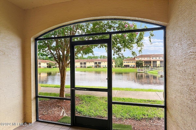 doorway to outside featuring a water view, plenty of natural light, and light tile patterned floors