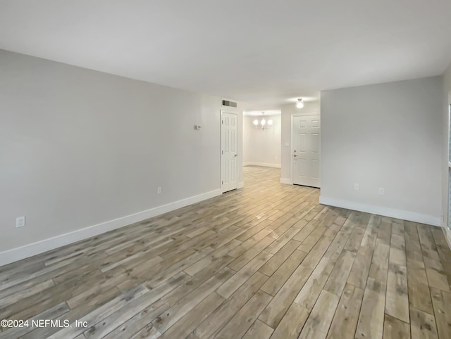 unfurnished room with light hardwood / wood-style floors and an inviting chandelier