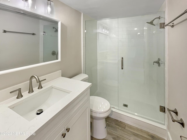 bathroom featuring wood-type flooring, vanity, toilet, and an enclosed shower