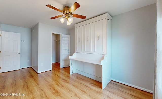 unfurnished bedroom with a walk in closet, ceiling fan, and light wood-type flooring