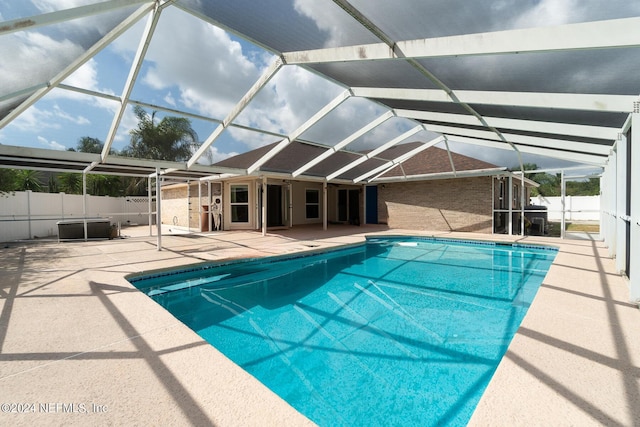 view of swimming pool featuring glass enclosure and a patio