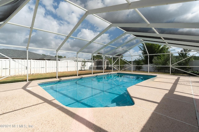 view of pool with a patio area, a storage unit, and glass enclosure