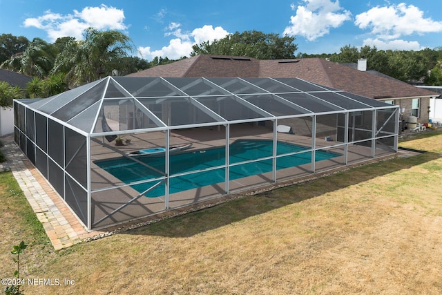 view of pool featuring a patio area, a lawn, and glass enclosure