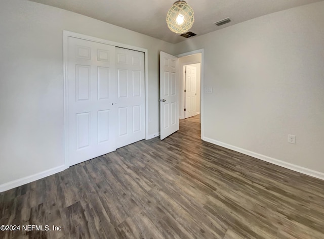 unfurnished bedroom with a closet and dark hardwood / wood-style flooring