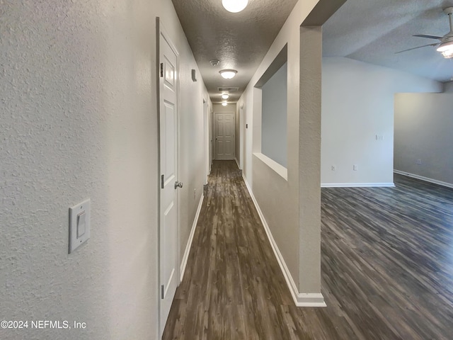 hallway with dark hardwood / wood-style floors and a textured ceiling