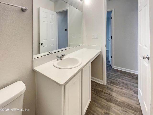 bathroom featuring toilet, vanity, and wood-type flooring