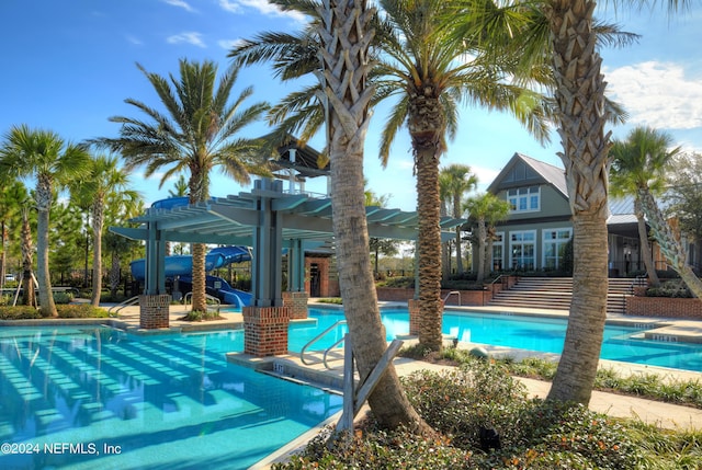 view of swimming pool with a pergola and a water slide