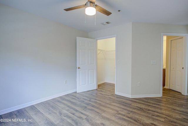 unfurnished bedroom with a closet, hardwood / wood-style flooring, a spacious closet, and ceiling fan