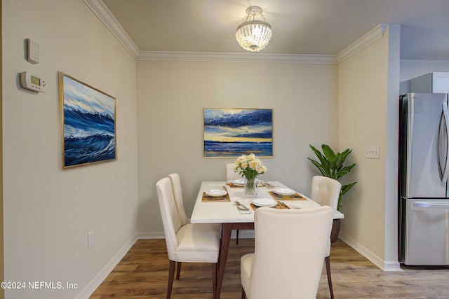 dining space with crown molding, a notable chandelier, and hardwood / wood-style flooring