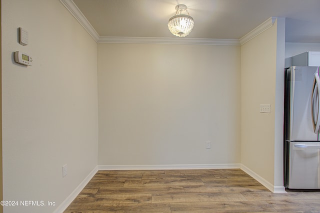 unfurnished dining area featuring light hardwood / wood-style floors, an inviting chandelier, and crown molding