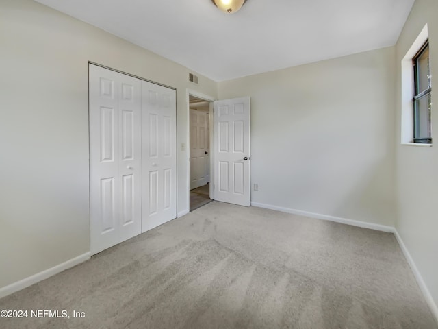 unfurnished bedroom with light colored carpet and a closet