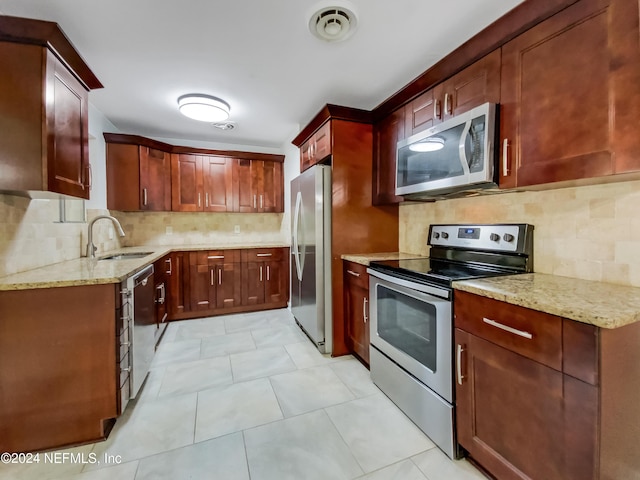 kitchen with decorative backsplash, light stone counters, sink, and appliances with stainless steel finishes