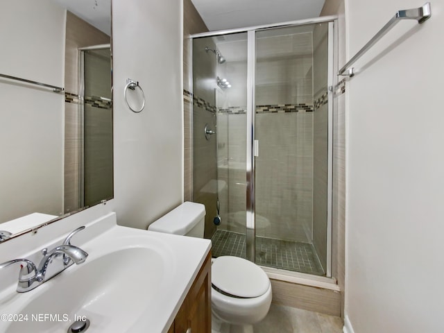 bathroom with vanity, toilet, and a shower with door