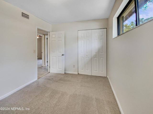 unfurnished bedroom featuring light carpet and a closet