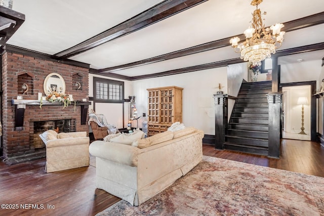 living room featuring a brick fireplace, dark hardwood / wood-style floors, an inviting chandelier, and beam ceiling