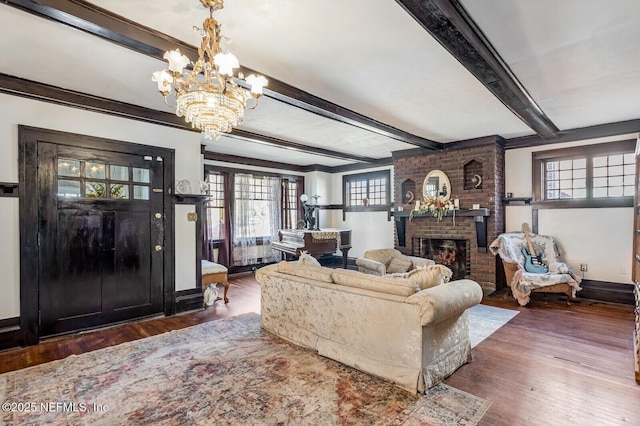 living room with dark hardwood / wood-style flooring, a brick fireplace, a notable chandelier, and beamed ceiling